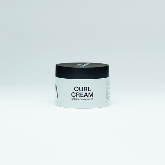 Jar of aura curl cream with black lid and white body on a light gray background