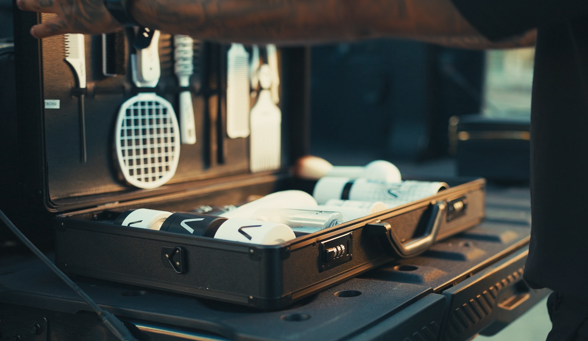 Open suitcase with  AURA toiletries on a vehicle's open trunk