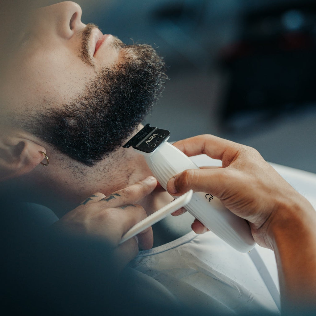 Barber using  aura trimmer on a customer's head in a barbershop setting