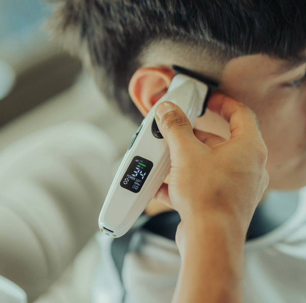 Person using a digital aura trimmer for haircut