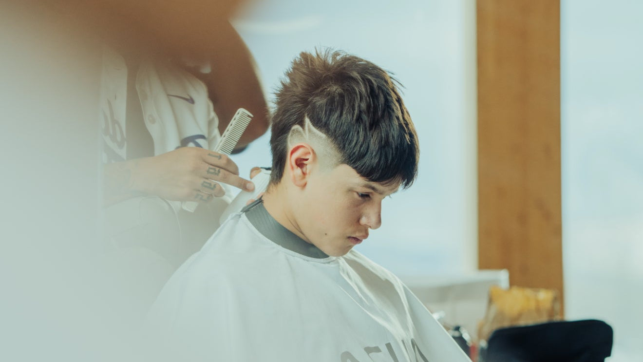 Person getting a haircut in a salon with a focus on the hair cutting process WITH AURA CAPES